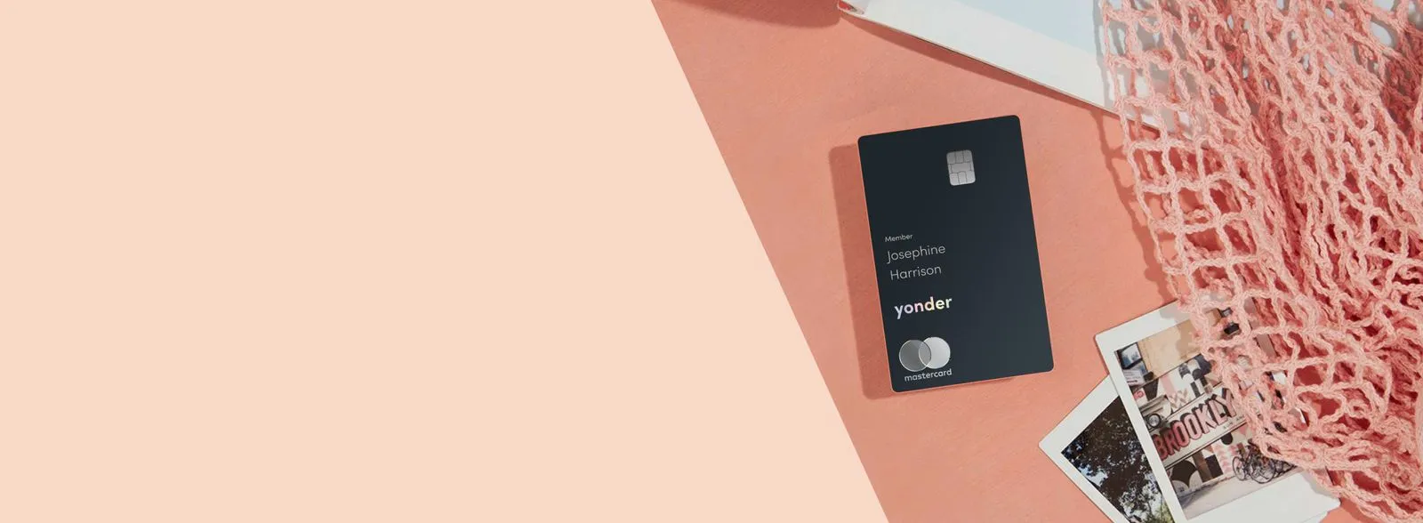 A Yonder Mastercard on a coral backdrop beside a stack of polaroid photos